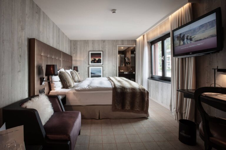 Doppelzimmer im Hotel Grischa mit Polsterbett, Fellplaid, Ledersessel und Flatscreen