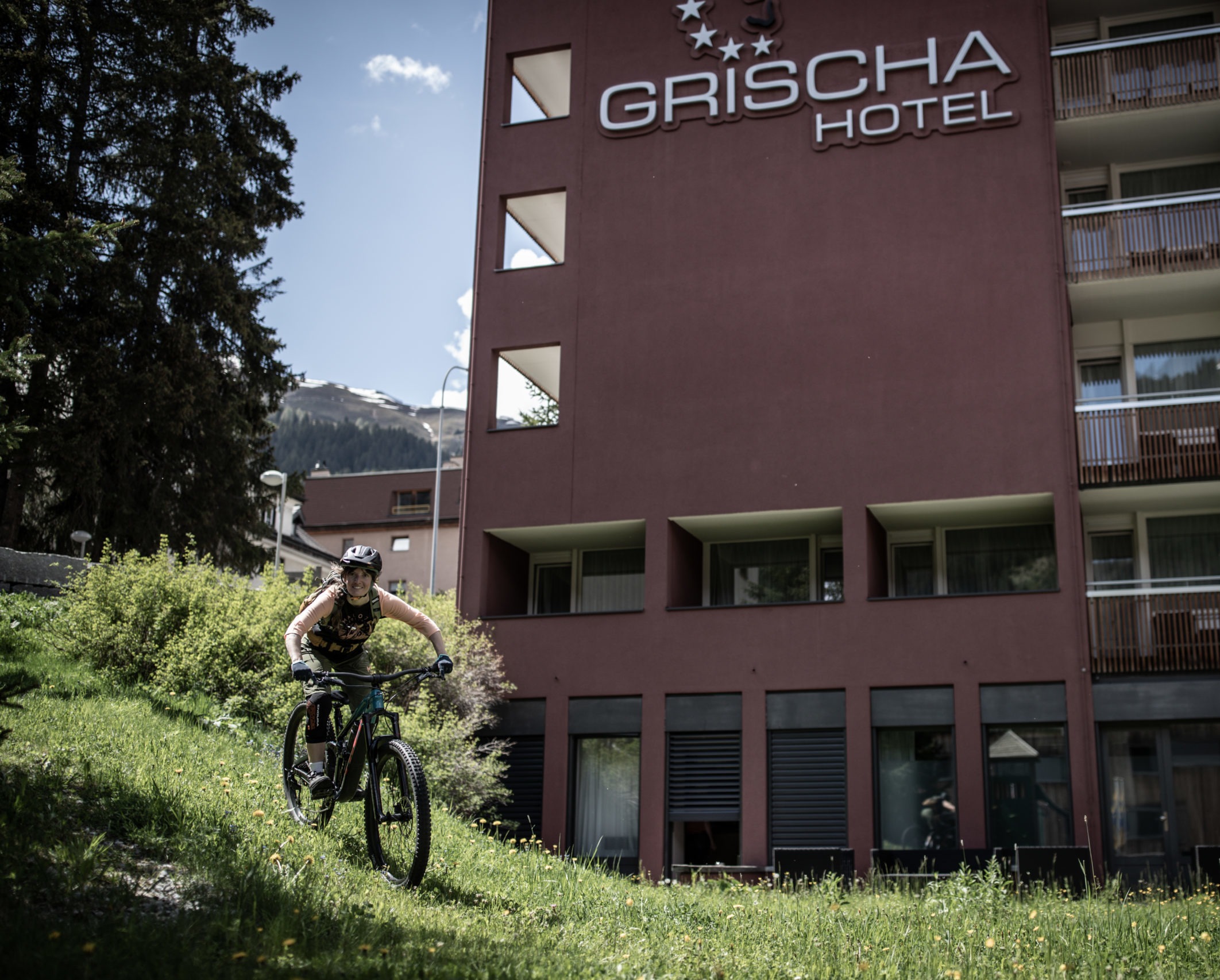 Mountainbikerin fährt über die Wiese vor dem Hotel Grischa in Davos