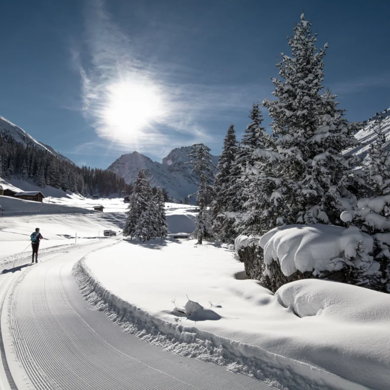 Langläufer auf der frisch gespurten Loipe im verschneiten Tal bei Davos
