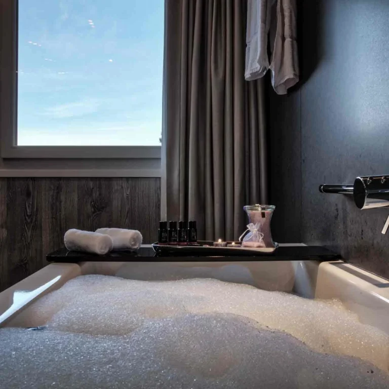 Badewanne mit Schaumbad, Pflegeprodukten und Blick aus dem Fenster
