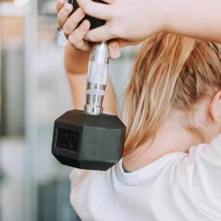 Frau trainiert im Fitnessraum mit einer Kurzhantel