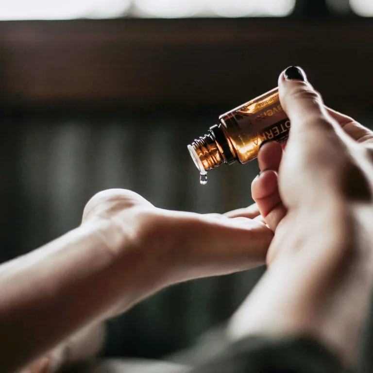 Massageöl wird aus einem Fläschchen auf die Hand getropft